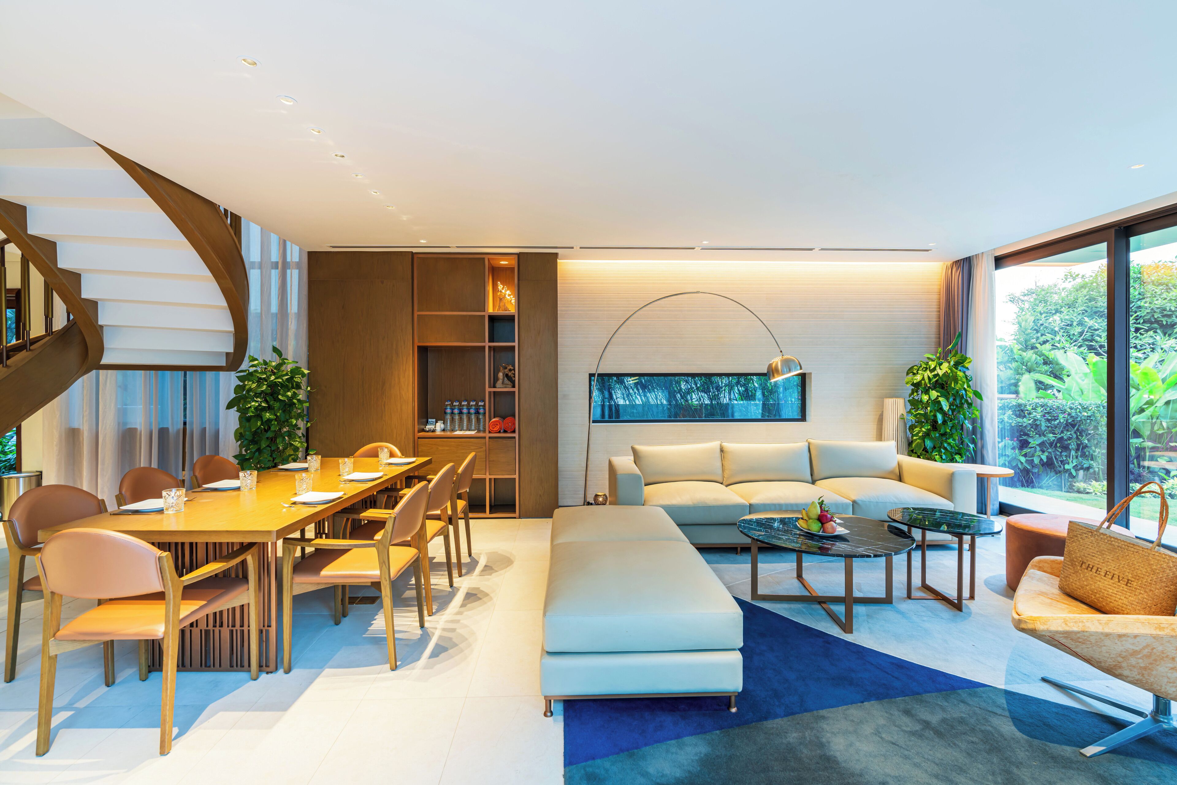 Un salon moderne comprenant un coin repas, un canapé, une table basse et un escalier.
