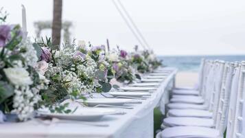 A long table with white tablecloths and chairs, decorated with floral arrangements.