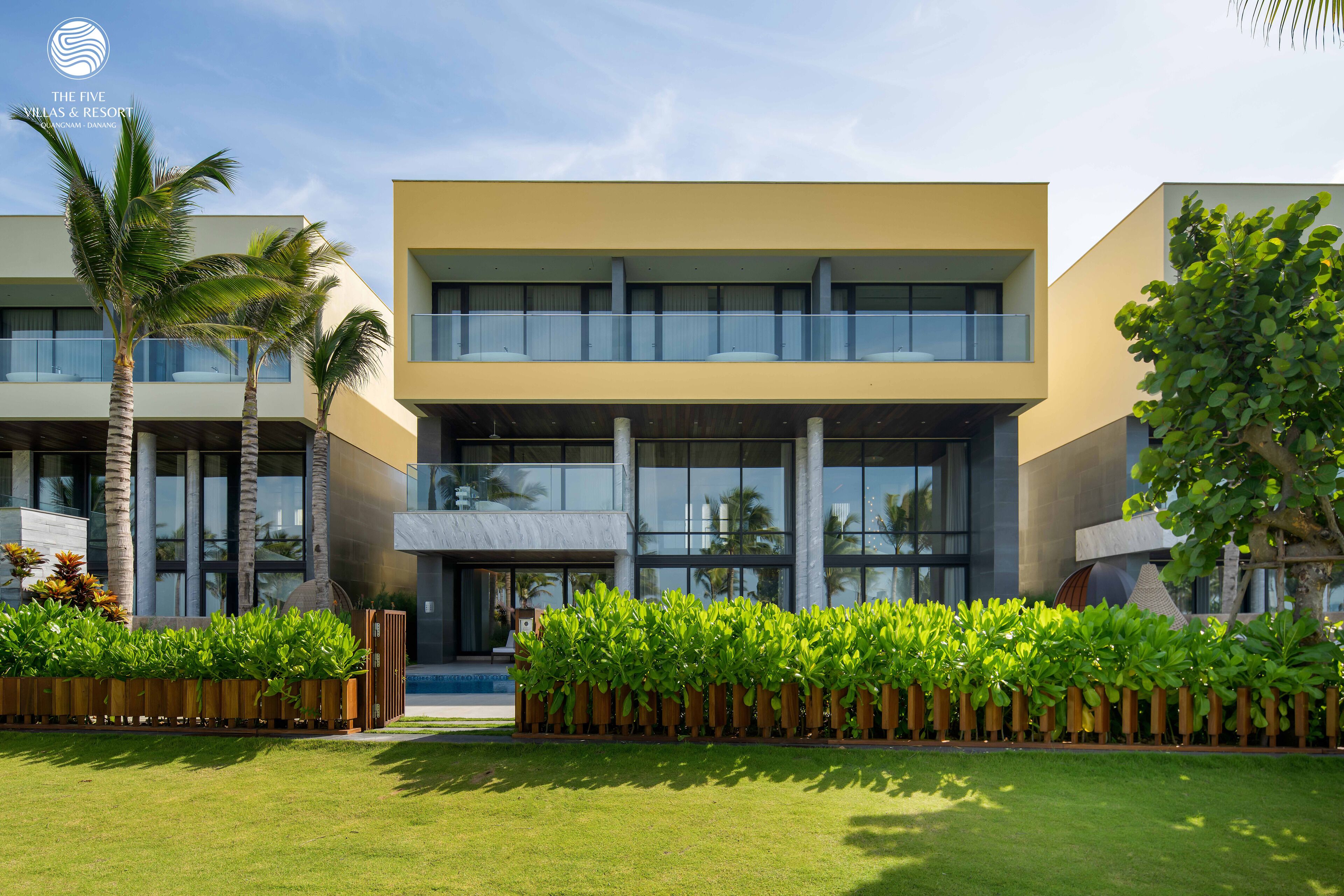 A modern hotel with a flat roof, large windows, and a well-maintained lawn.