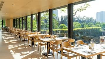 A spacious dining area with large windows, wooden tables, and chairs.