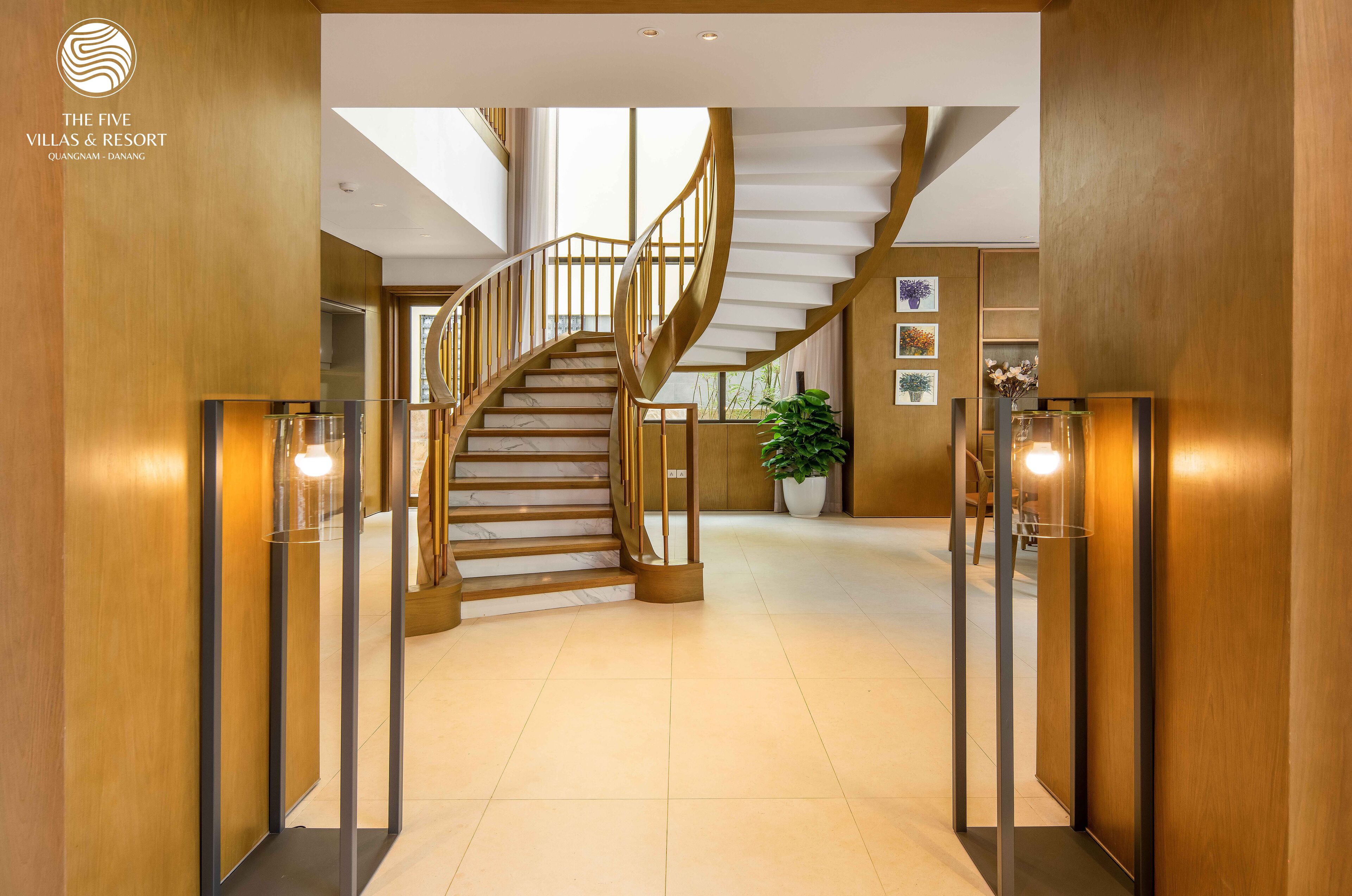 Un hall d’hôtel moderne avec un escalier en marbre, des murs en bois et une grande plante en pot.
