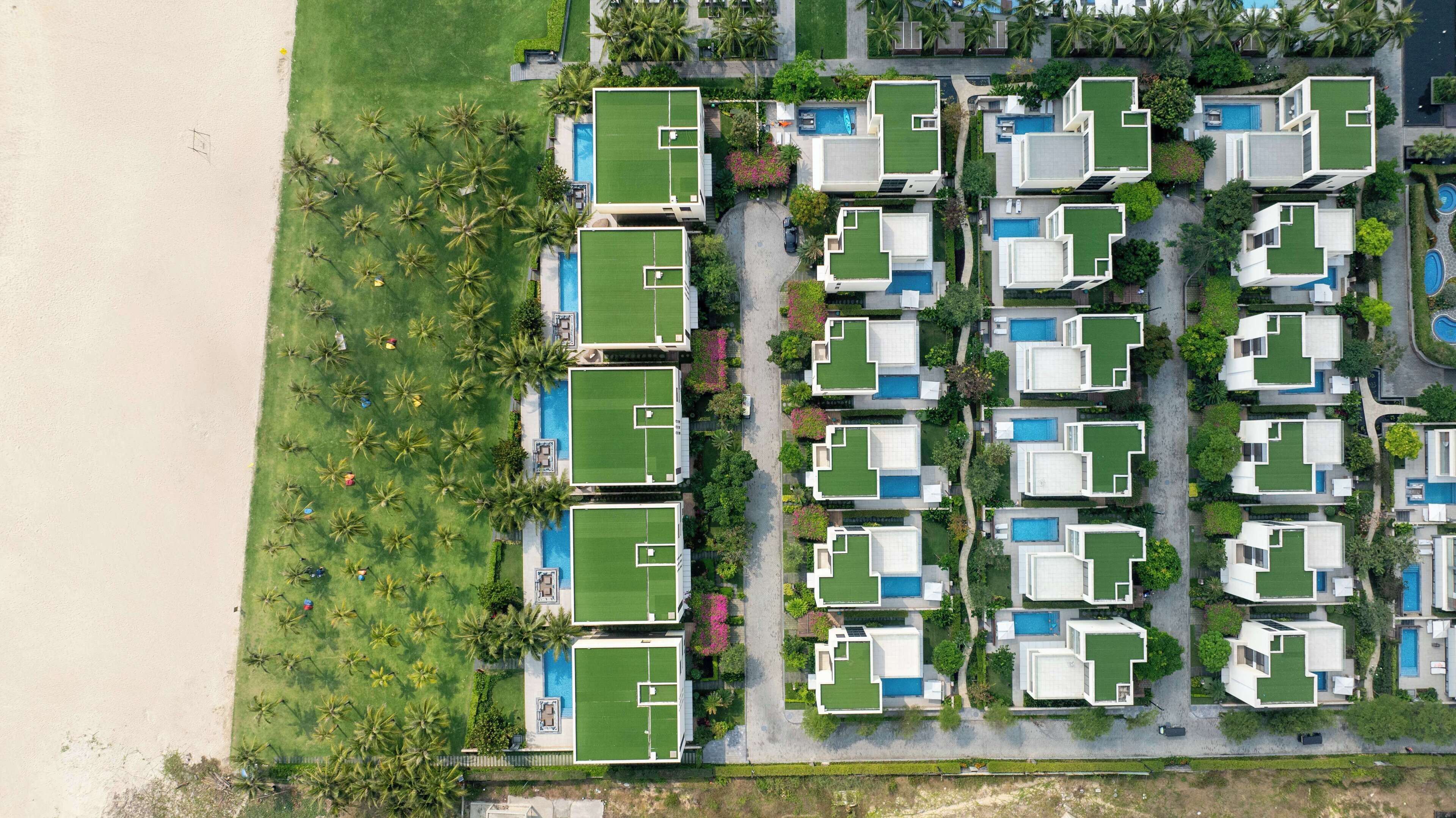 Eine Vogelperspektive zeigt ein Resort mit mehreren Gebäuden, jedes mit einem Pool und von Palmen umgeben.