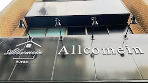 The exterior of the Allcomen Hotel with a modern design, featuring a prominent sign and a series of steps leading up to the entrance. - Allcomein Hotel (Tokyo)