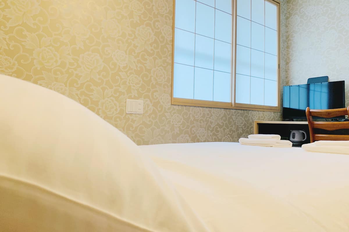 A hotel room with a bed, a television, and a chair.