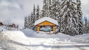 A snow-covered lodge with a wooden structure and a sign that reads "Brew White." - True Ski in/Ski out Hot tub In the village (Big White)