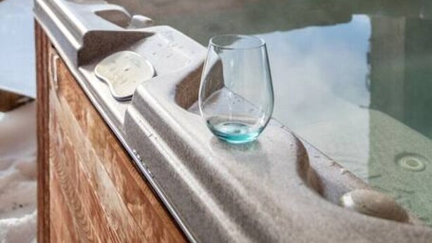 A hot spring area with a wooden bench and a glass of water. - True Ski in/Ski out Hot tub In the village (Big White)