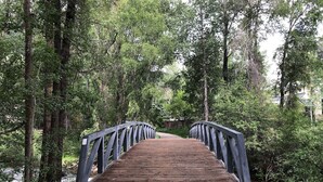 Un pont en bois avec des garde-corps en métal, situé dans une zone boisée.