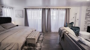 Une chambre à coucher moderne avec un grand lit, un canapé et un fauteuil.