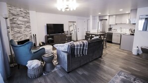 Un salon moderne avec un canapé, un téléviseur et un coin repas.
