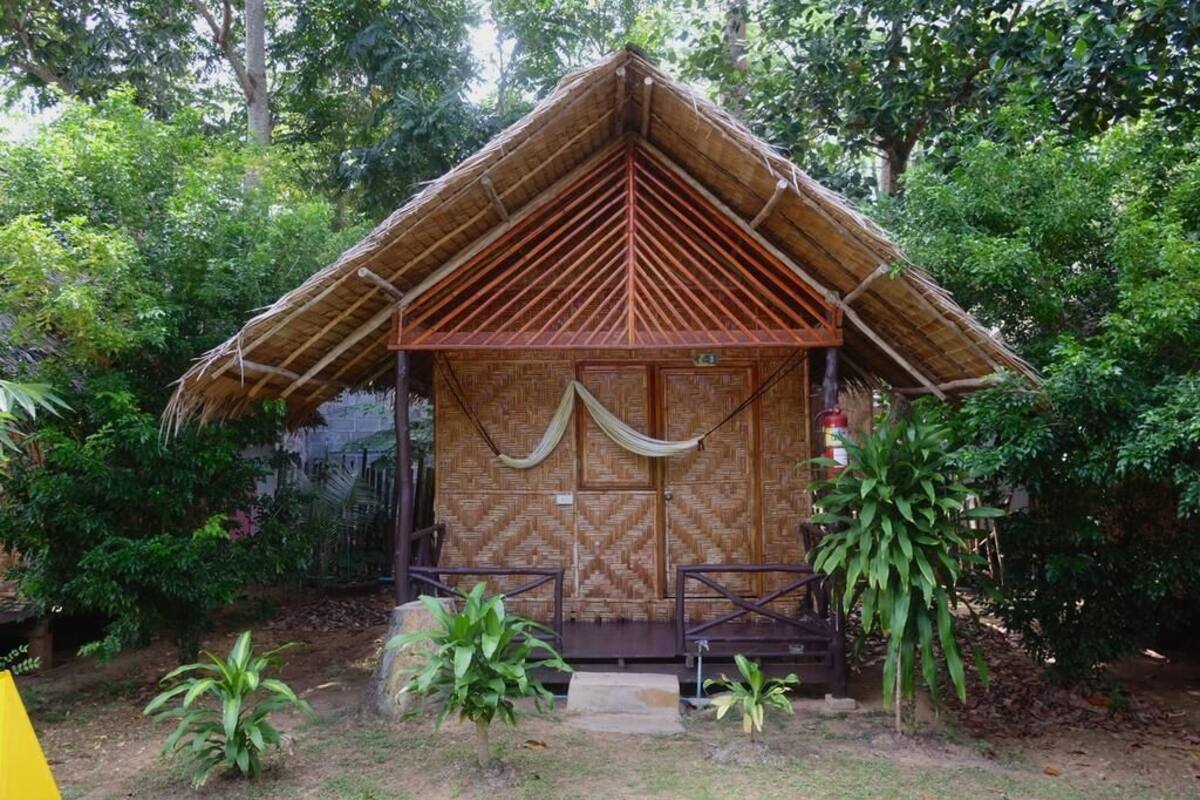 Une petite cabane rustique, dotée d’un toit de chaume, entourée d’une végétation luxuriante.
