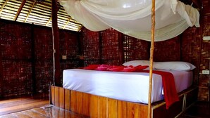 Una habitación con una cama bajo un dosel, paredes y suelo de madera.