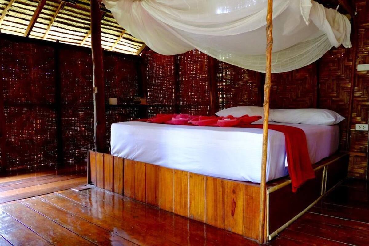 Une chambre avec un lit sous un dais, des murs en bois et un plancher en bois.