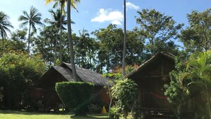 Un resort tropical con cabañas de techo de paja, exuberante vegetación y un cielo azul claro.