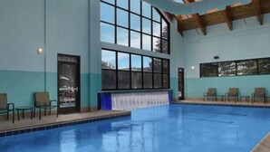 An indoor swimming pool with clear blue water, surrounded by lounge chairs and a large window. - Streamside at Vail Birch (Vail)