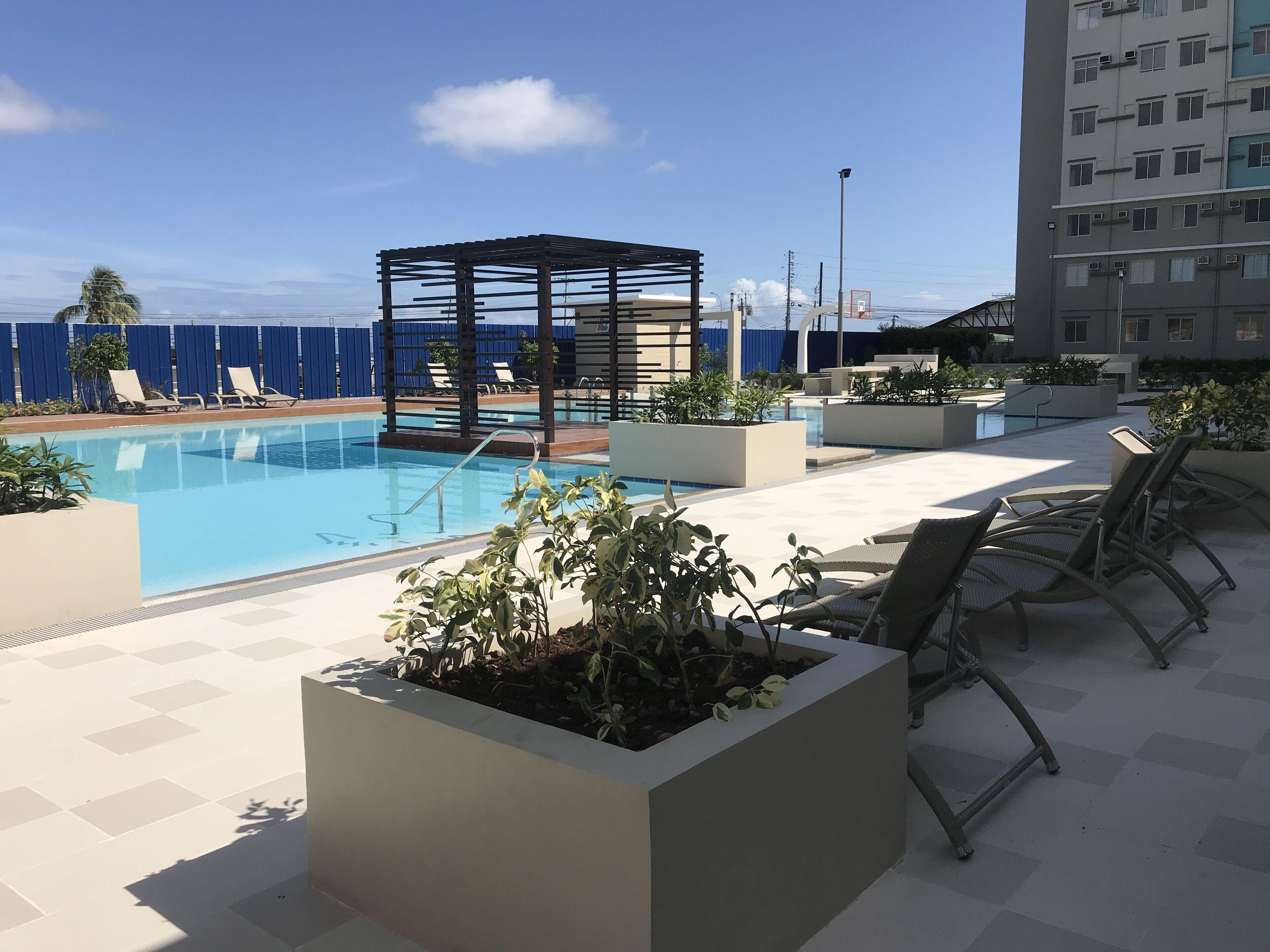 Zona de piscina al terrat amb gandules, una pèrgola i vista al mar.