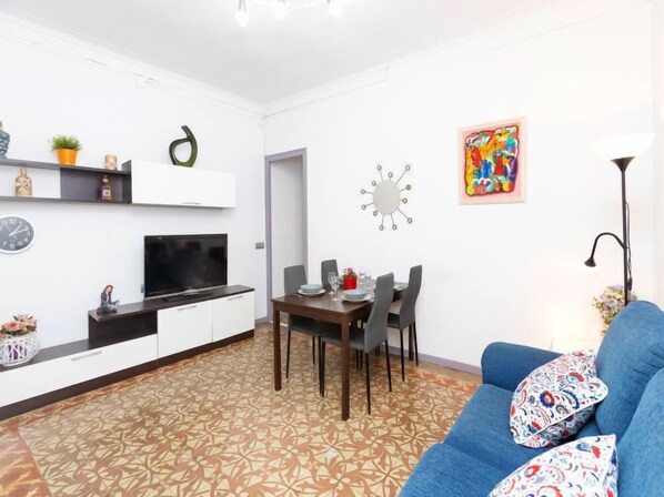 A modern living room with a TV, dining table, and blue sofa.