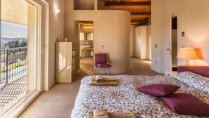 A bedroom with a large bed, a chair, a lamp, and a view of a balcony. - Modern villa with heated pool and Jacuzzi, near Ripe, just 20 minutes from the beach of Senigallia (Trecastelli)