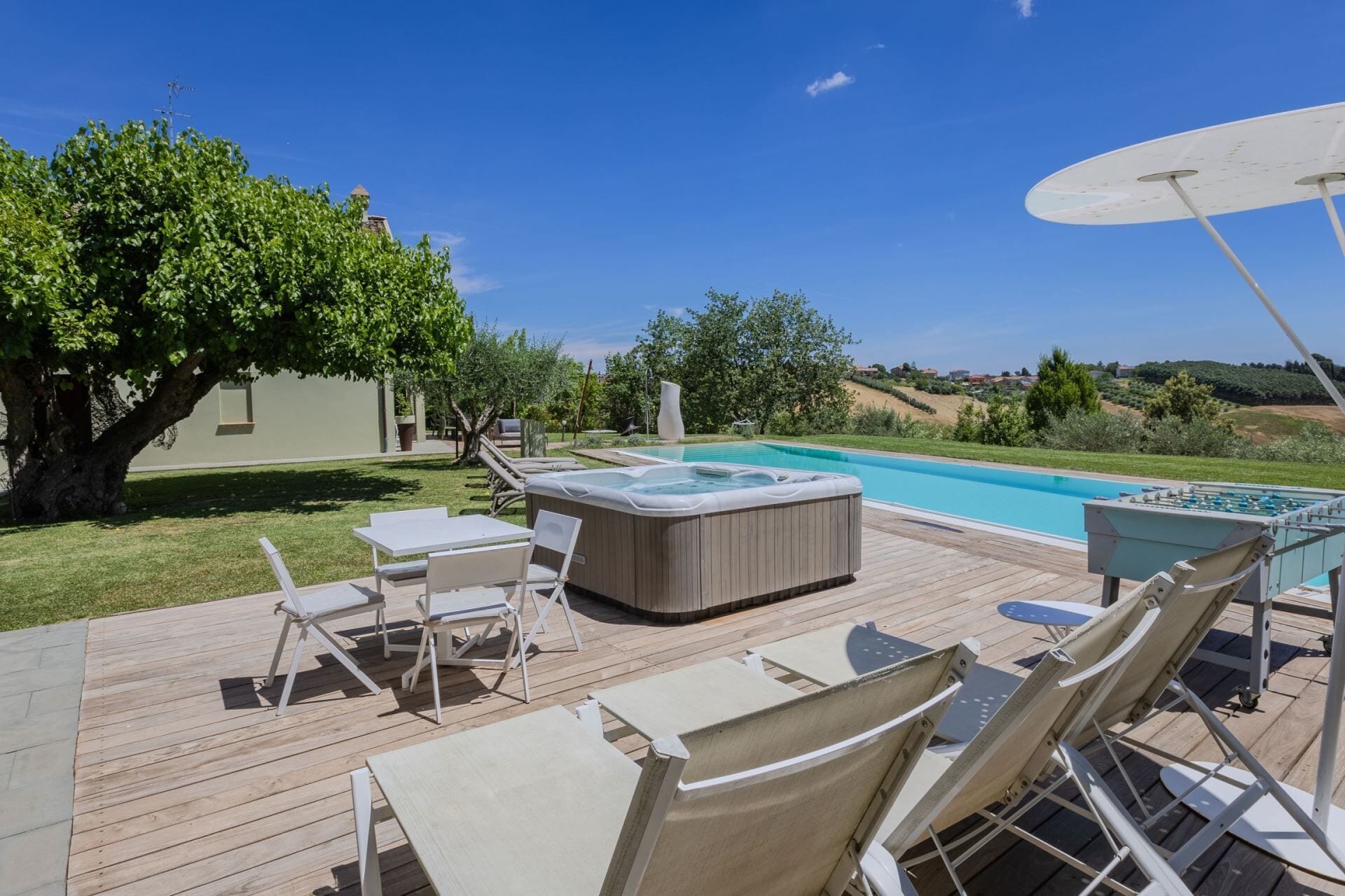 A wooden deck with outdoor furniture, a hot tub, and a swimming pool.
