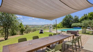 An outdoor patio with a wooden table and chairs, a pool, and a view of the countryside. - Modern villa with heated pool and Jacuzzi, near Ripe, just 20 minutes from the beach of Senigallia (Trecastelli)