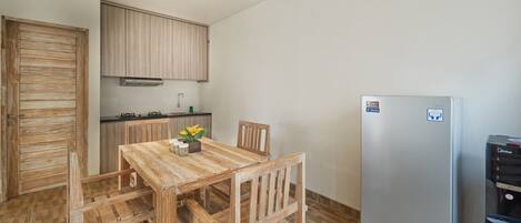 Een kleine keuken met houten kastjes, een roestvrijstalen koelkast en een eettafel met stoelen.