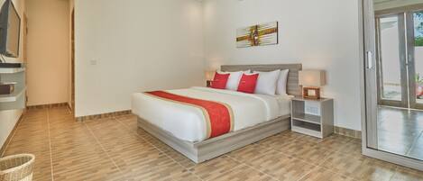 Una habitación de hotel moderna con una cama grande, un televisor de pantalla plana, aire acondicionado montado en la pared y una puerta corrediza de vidrio al exterior.