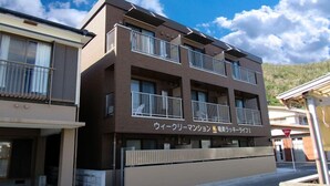 A multi-story building with balconies and a sign in Japanese. - Amami Lucky Life (Amami)