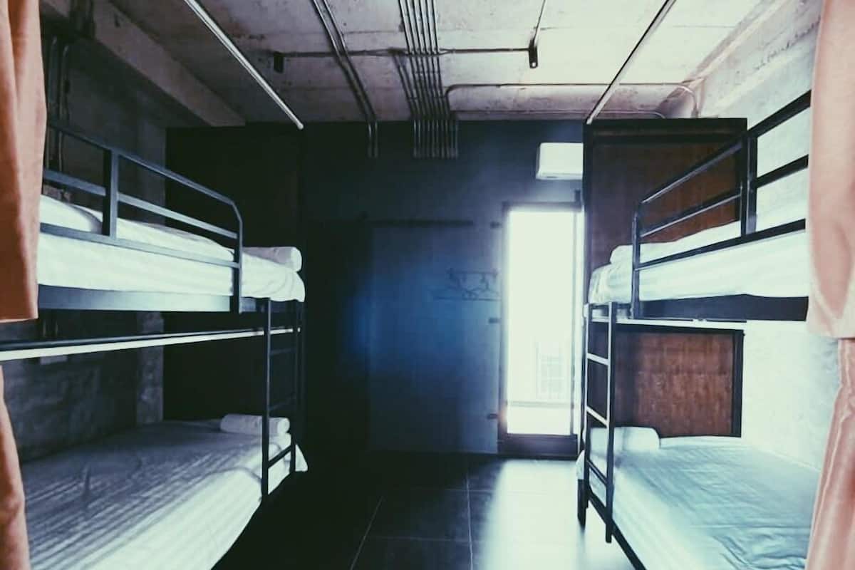 Ein Schlafsaalzimmer mit Stockbetten, Fliesenboden und einem Fenster, das für natürliches Licht sorgt.