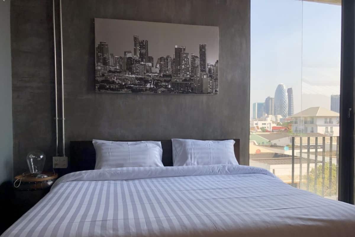 Ein Hotelzimmer mit einem großen Bett, Blick auf die Stadt und modernem Design.