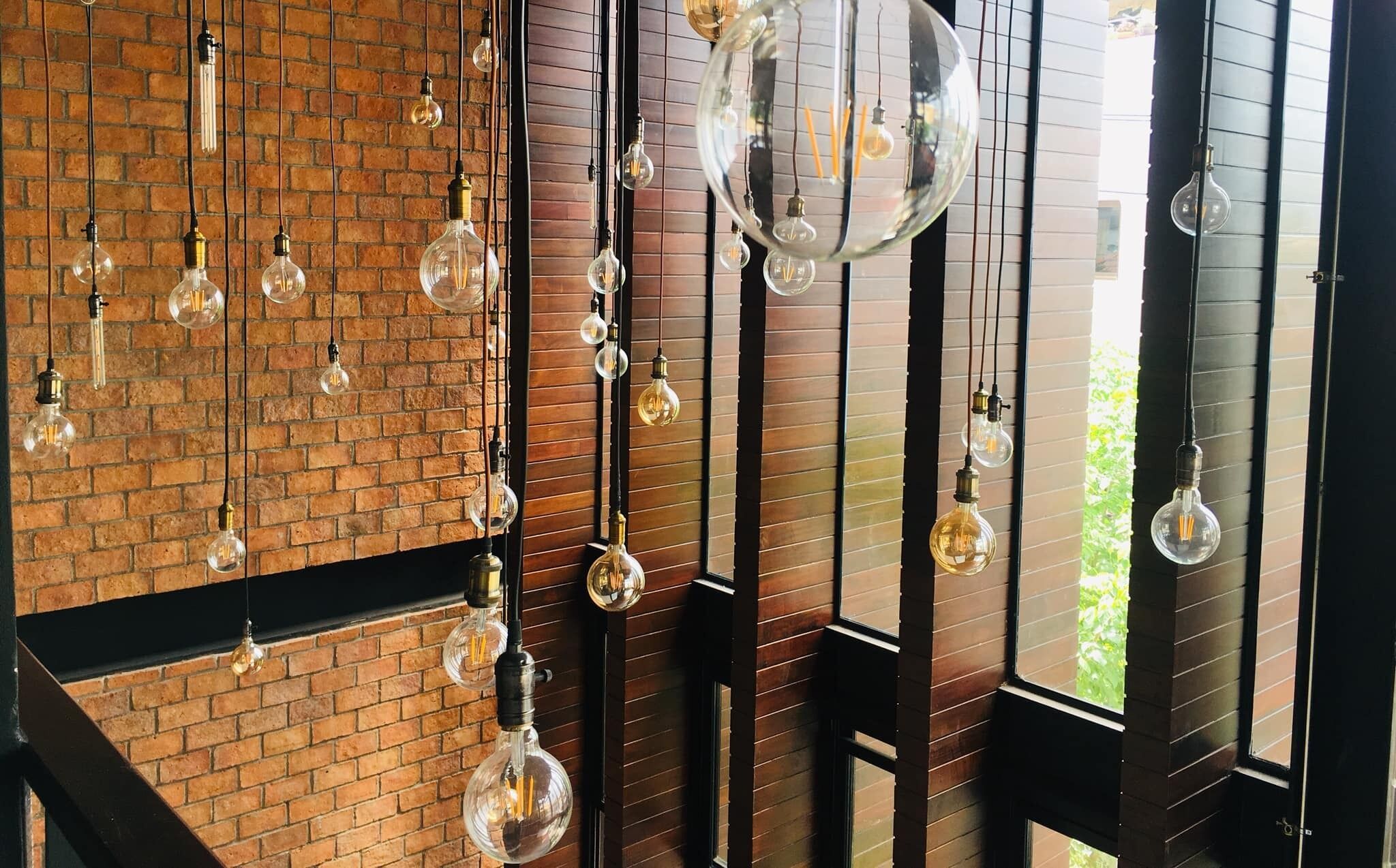 Une pièce avec un mur en briques et plusieurs luminaires suspendus.