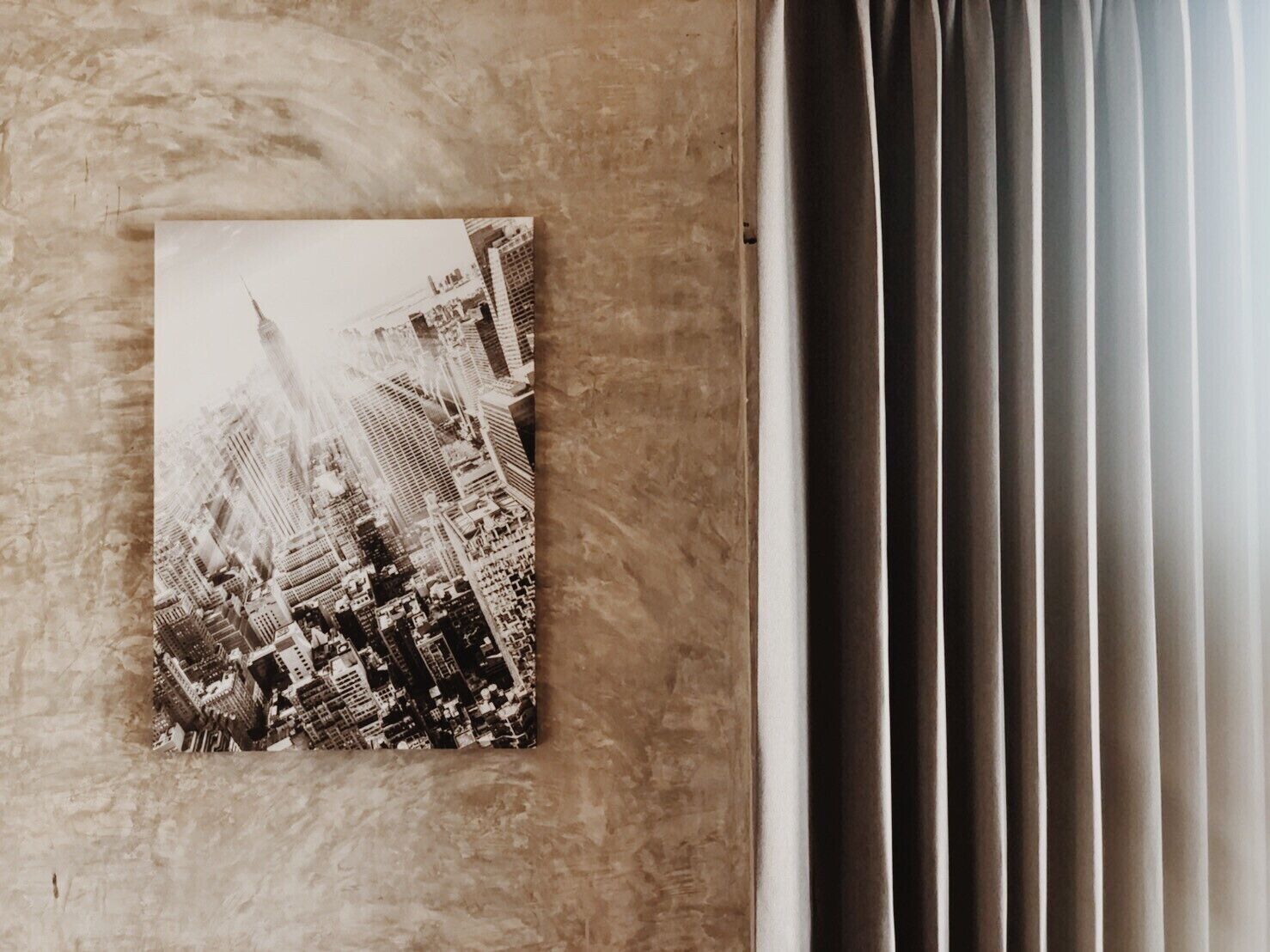 A photograph of a cityscape with tall buildings, mounted on a textured wall.