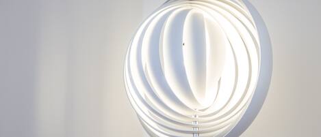 A modern, spherical pendant light fixture with a white, ribbed design against a plain wall.