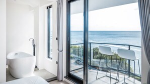 Une salle de bain moderne dotée d’une grande baignoire, d’une douche et d’un balcon offrant une vue sur l’océan.