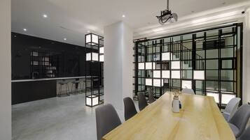 A modern conference room with a large wooden table, grey chairs, and a projector.