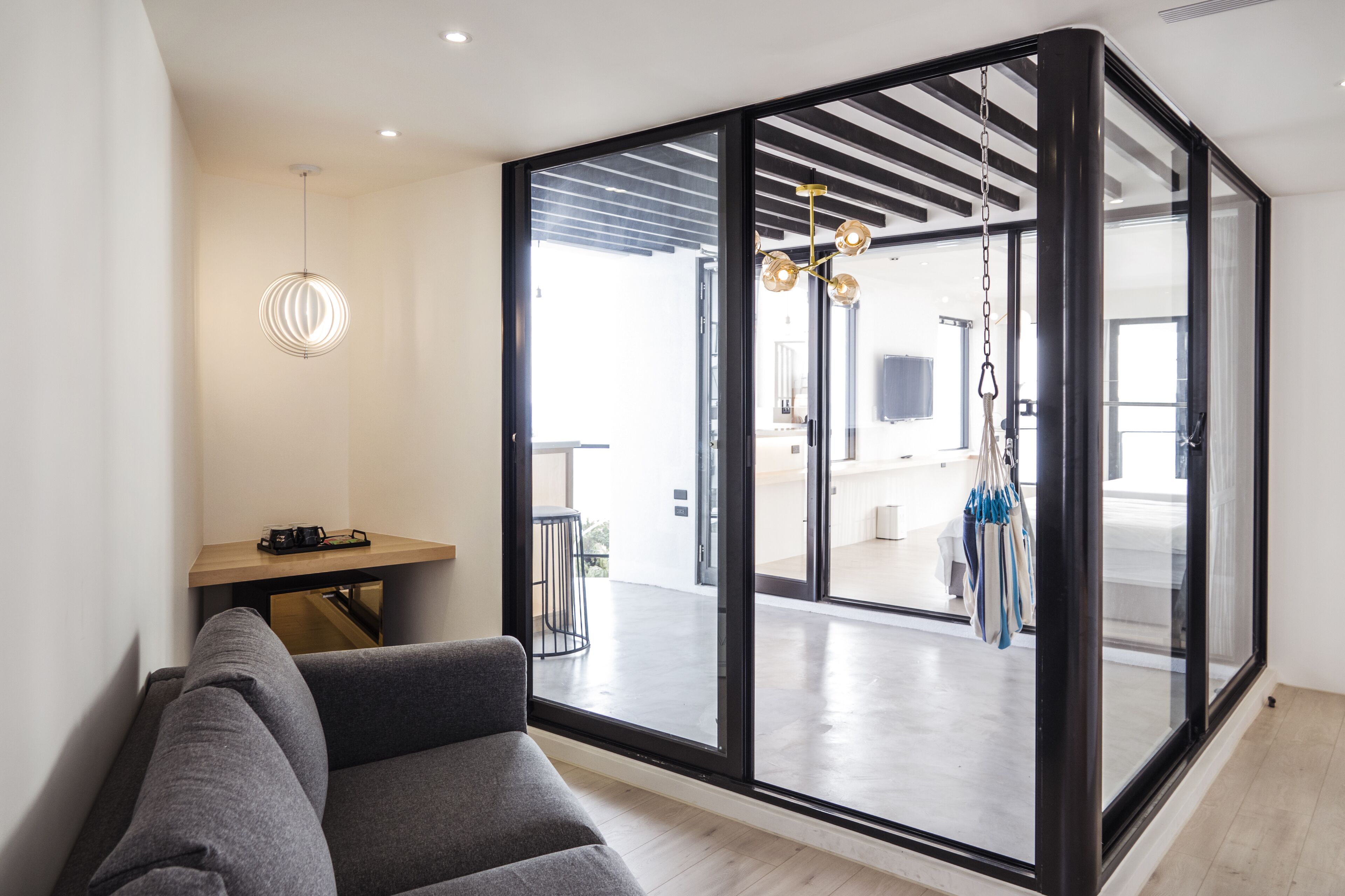 A modern living room with a grey sofa, a wooden coffee table, and a hanging light fixture.