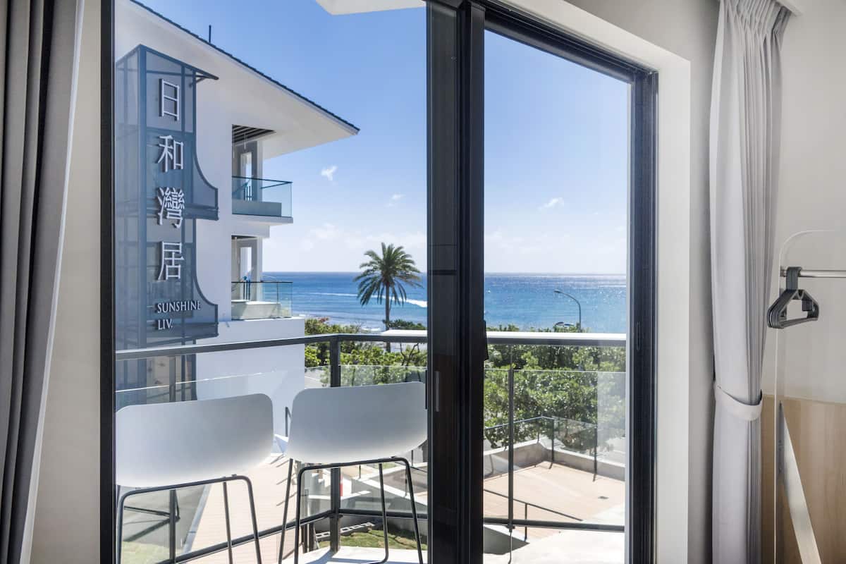 Un balcón con vista al mar, una silla blanca y un edificio con caracteres japoneses.