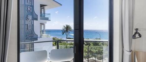 Un balcón con vista al mar, una silla blanca y un edificio con caracteres japoneses.