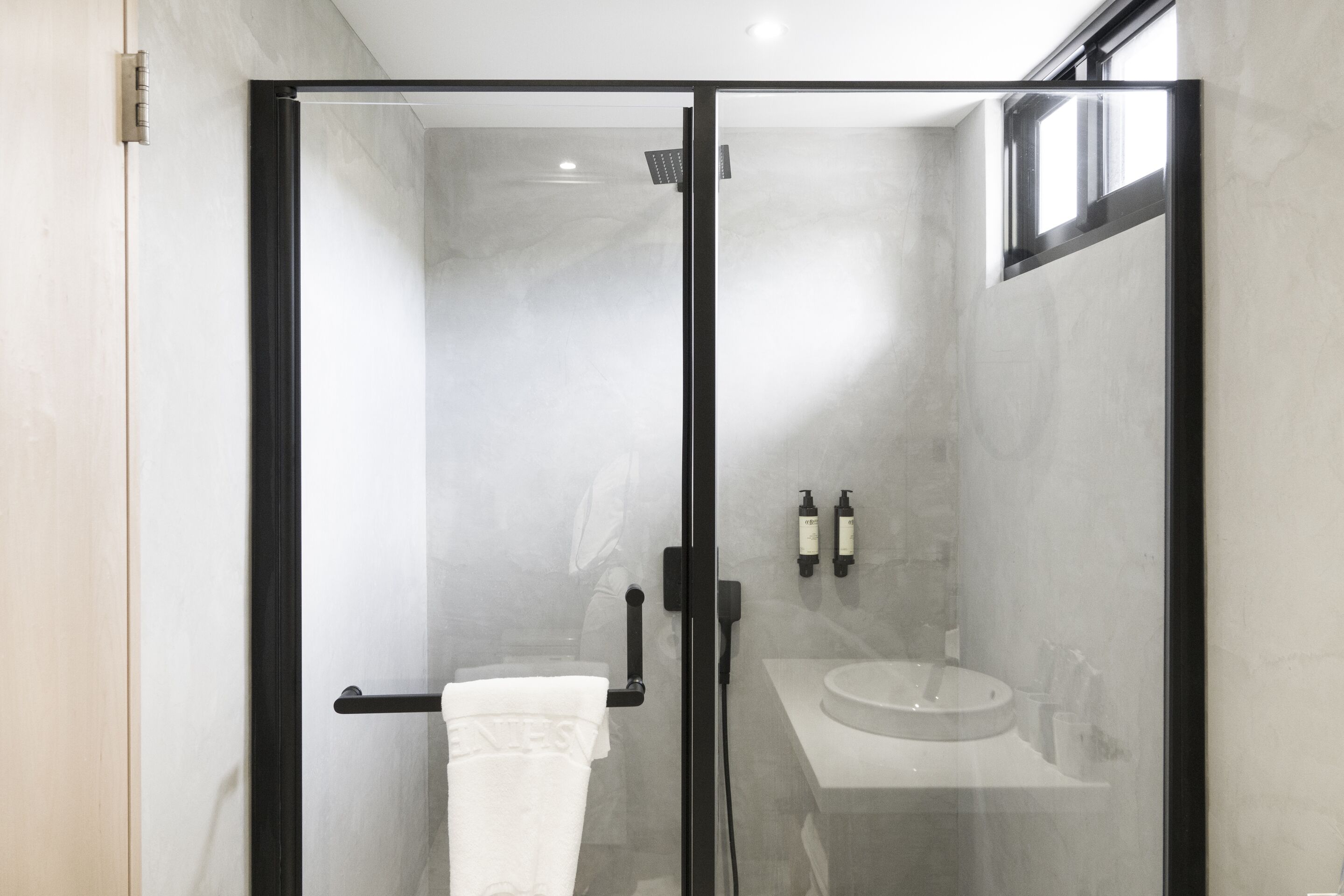 Une salle de bain moderne avec une douche à parois de verre, un lavabo blanc et un porte-serviettes.