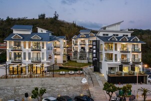 A modern hotel with multiple balconies, a central courtyard, and a view of the surrounding landscape.