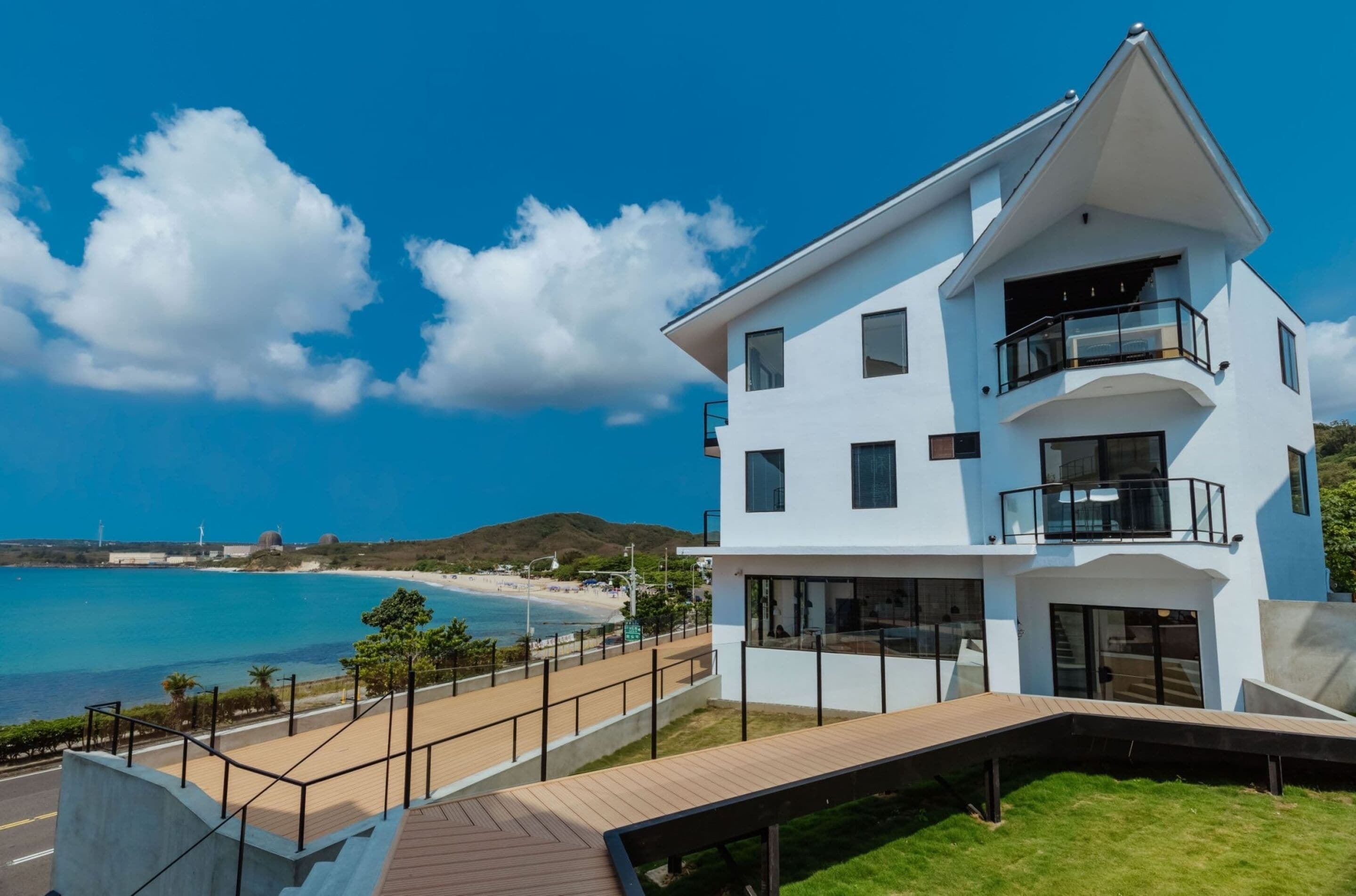Una casa moderna de dos pisos con balcón, con vista a una playa y al océano.