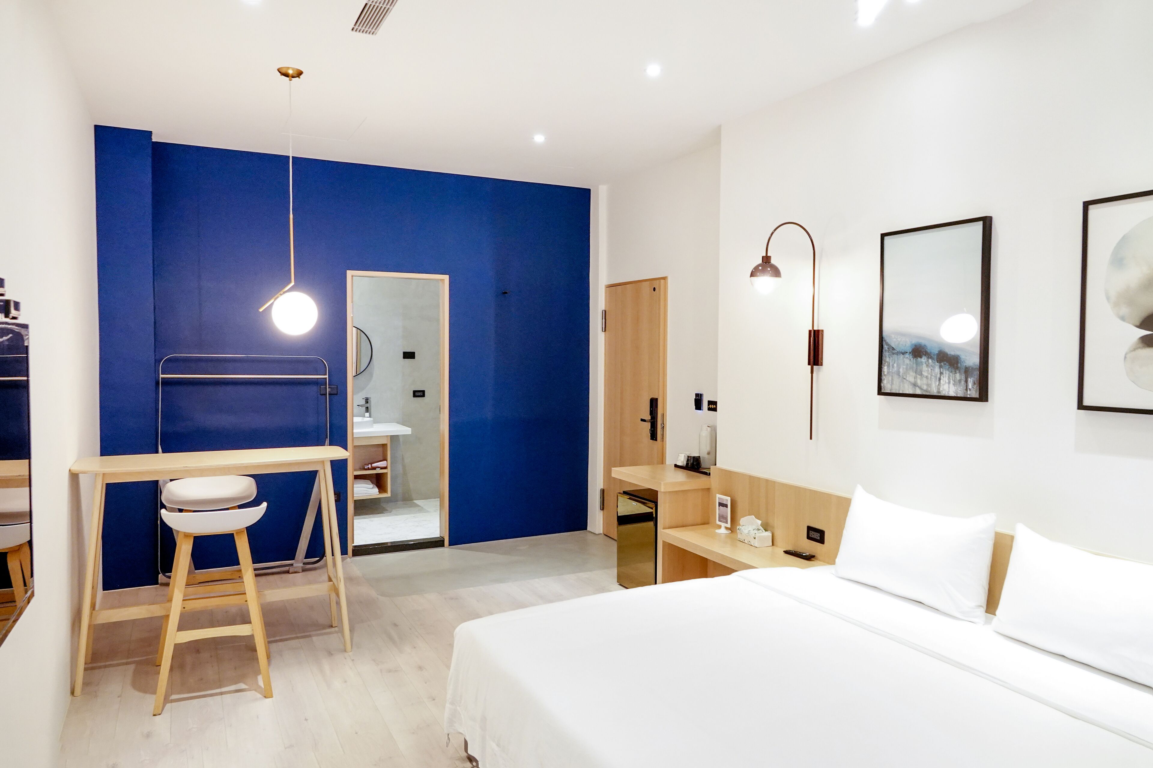 A modern hotel room with a bed, a desk, and a bathroom.