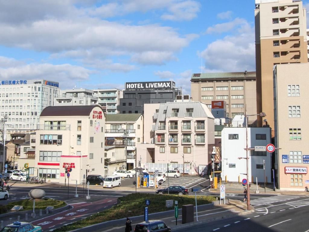 A cityscape with a prominent Hotel LIVEMAX building, a crosswalk, and various other buildings.