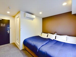 A hotel room with a bed, an air conditioning unit, a door, and a light switch on the wall. - Hotel Livemax Okayama West (Okayama)