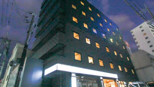 Et hotel med flere etager, oplyste vinduer og en markant indgang.