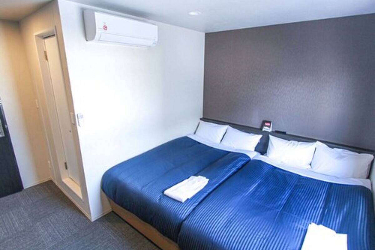 Una habitación de hotel con una cama grande, aire acondicionado de pared y una puerta.