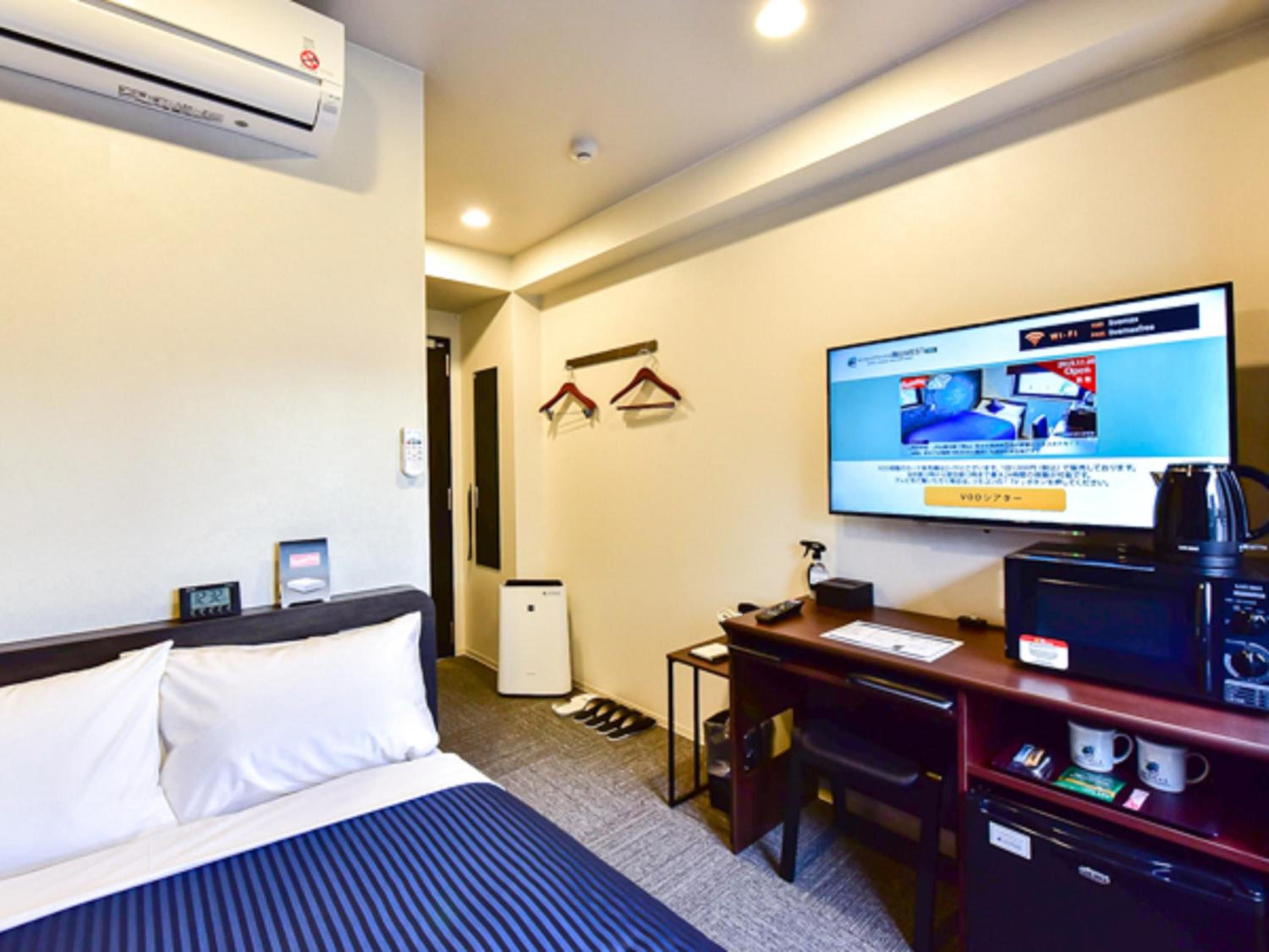 Ein Hotelzimmer mit einem Bett, einem Schreibtisch, einem Fernseher und einer Kaffeemaschine.