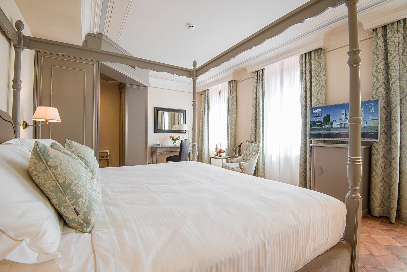 Un dormitorio amplio con una cama grande, un escritorio, una silla y vistas a la ciudad.