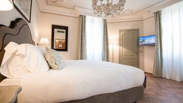Een hotelkamer met een groot bed, een kroonluchter, een televisie en een deur.