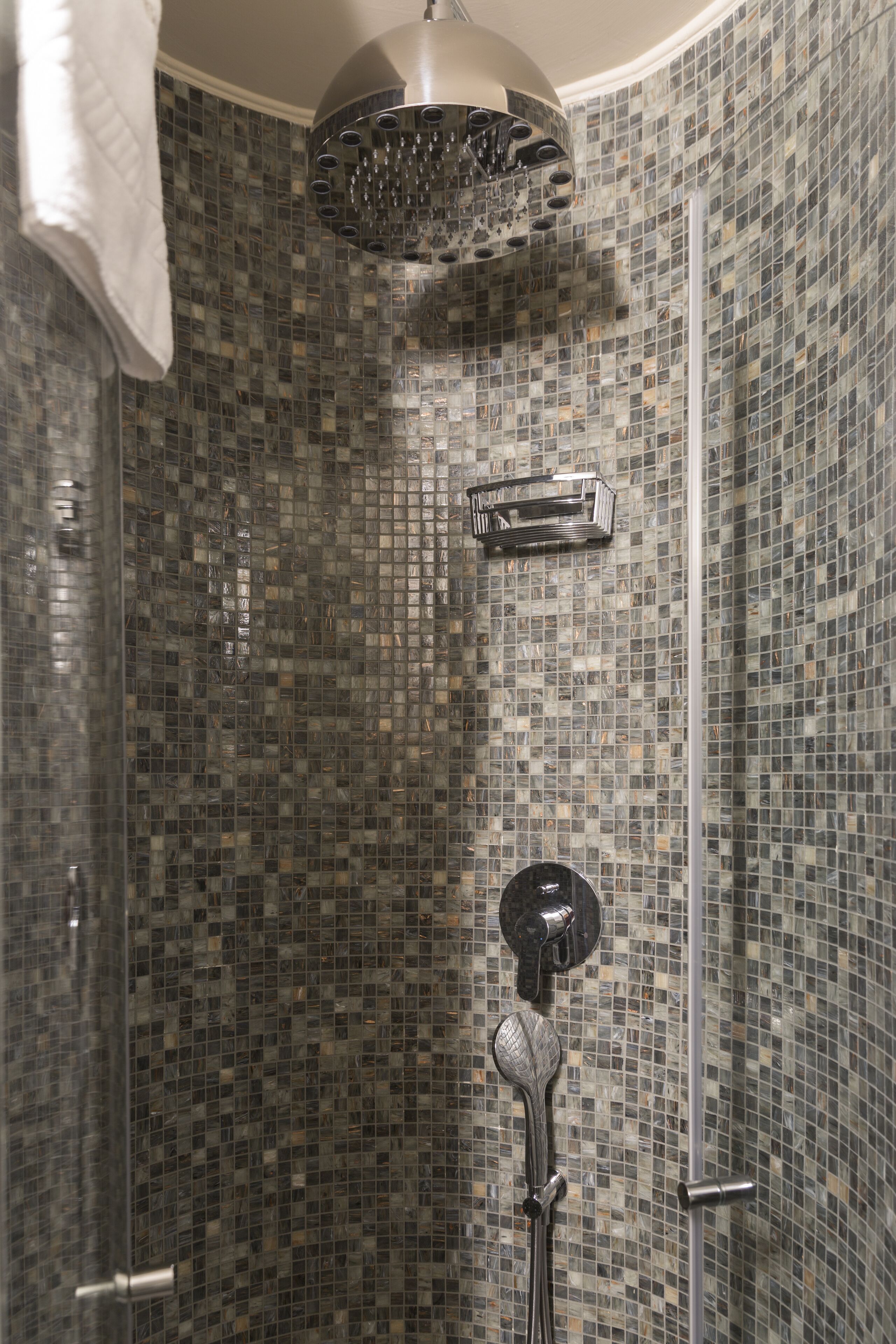 Ducha con paredes de azulejos decorativos y cabezal de ducha manual.