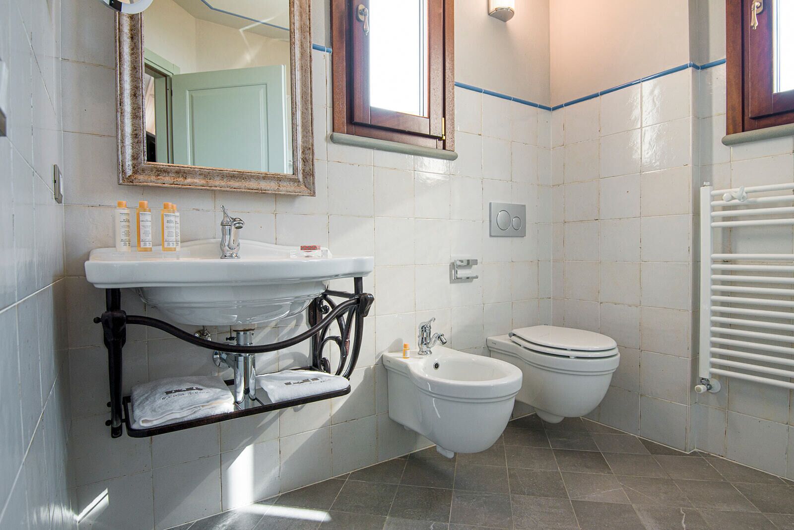 A bathroom with a white sink, a bidet, a toilet, and a mirror.