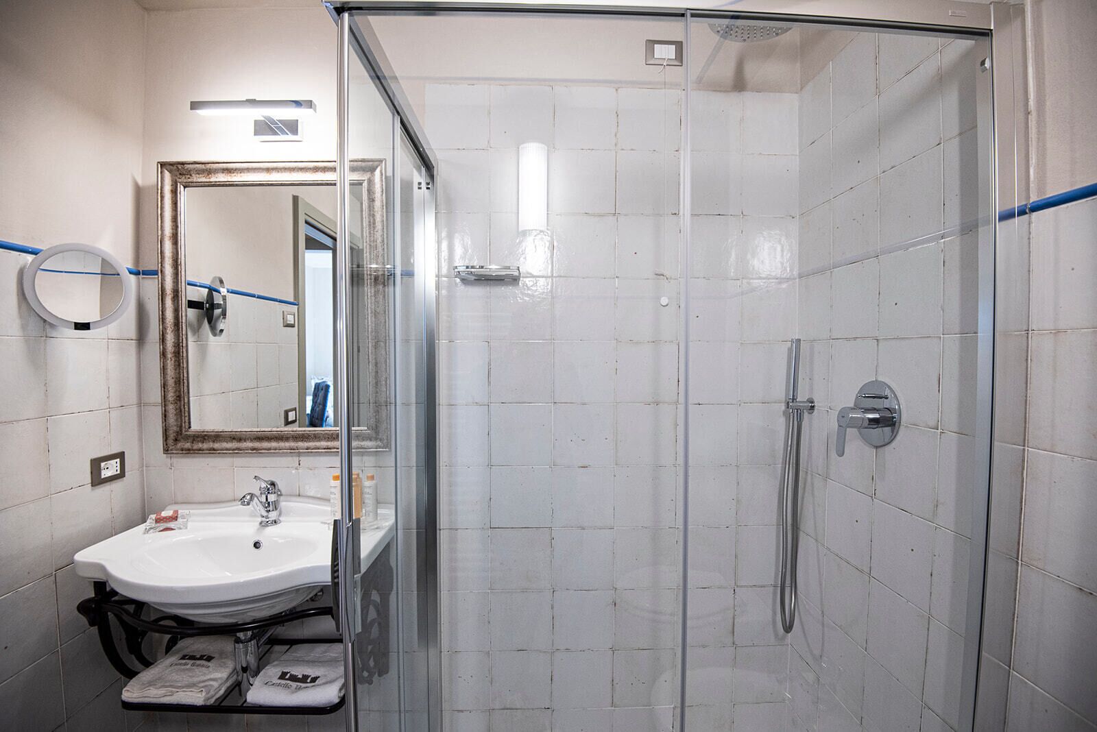 Une salle de bain avec une douche à parois de verre, un lavabo avec un miroir et un porte-serviettes.